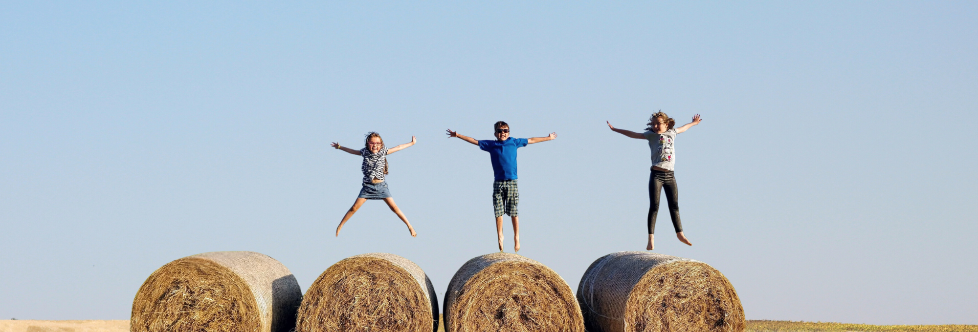 Barn som hoppar på höbalar, ser lyckliga ut