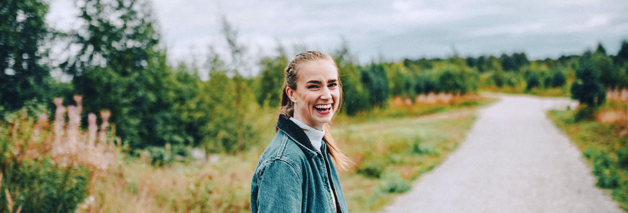 Kvinna som går på en grusväg och skrattar in i kameran