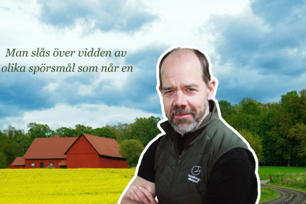 En man framför ett rapsfält och en röd lada