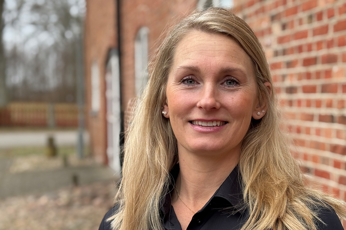 Porträtt av en leende ekonomirådgivare som står utomhus vid en tegelbyggnad.