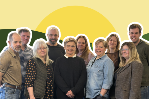 4 män och 6 kvinnor står i grupp och ler mot kameran mot en gul bakgrund