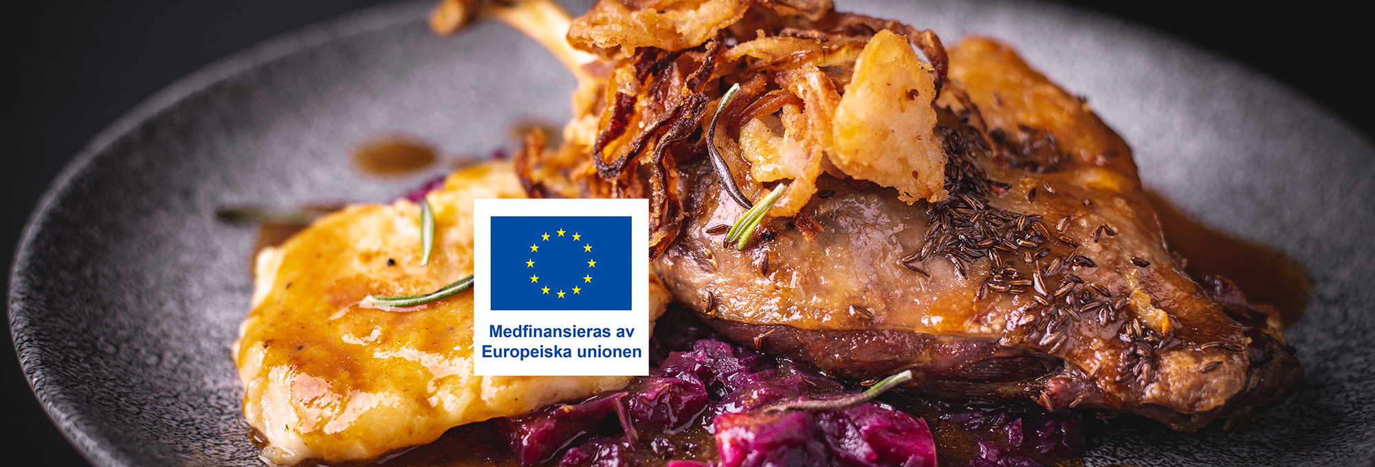 Stekt köttbit på tallrik serveras med sås, potatispuré eller gratäng, rödkål och krispig friterad lök, garnerat med rosmarin. Över maten ligger EU-flaggan och texten: “Medfinansieras av Europeiska unionen”.