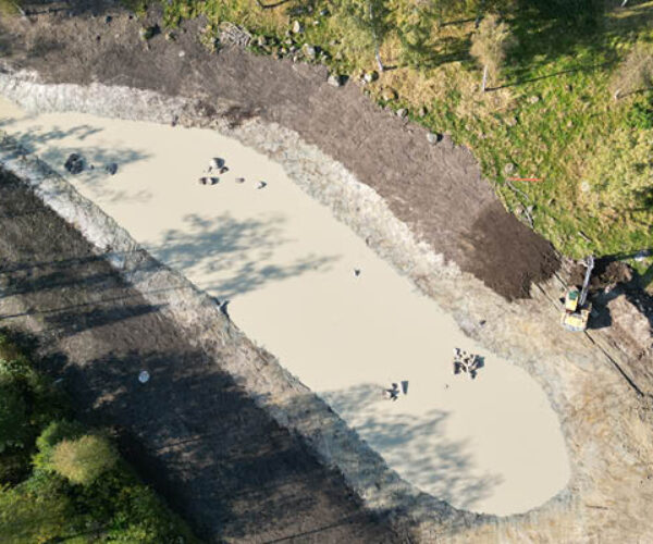 anlägga våtmark i Halland – flygbild av nyanlagd våtmark i jordbrukslandskap med stillastående vatten, grävd dammyta, jordmassor längs kanterna och grävmaskin som formar området